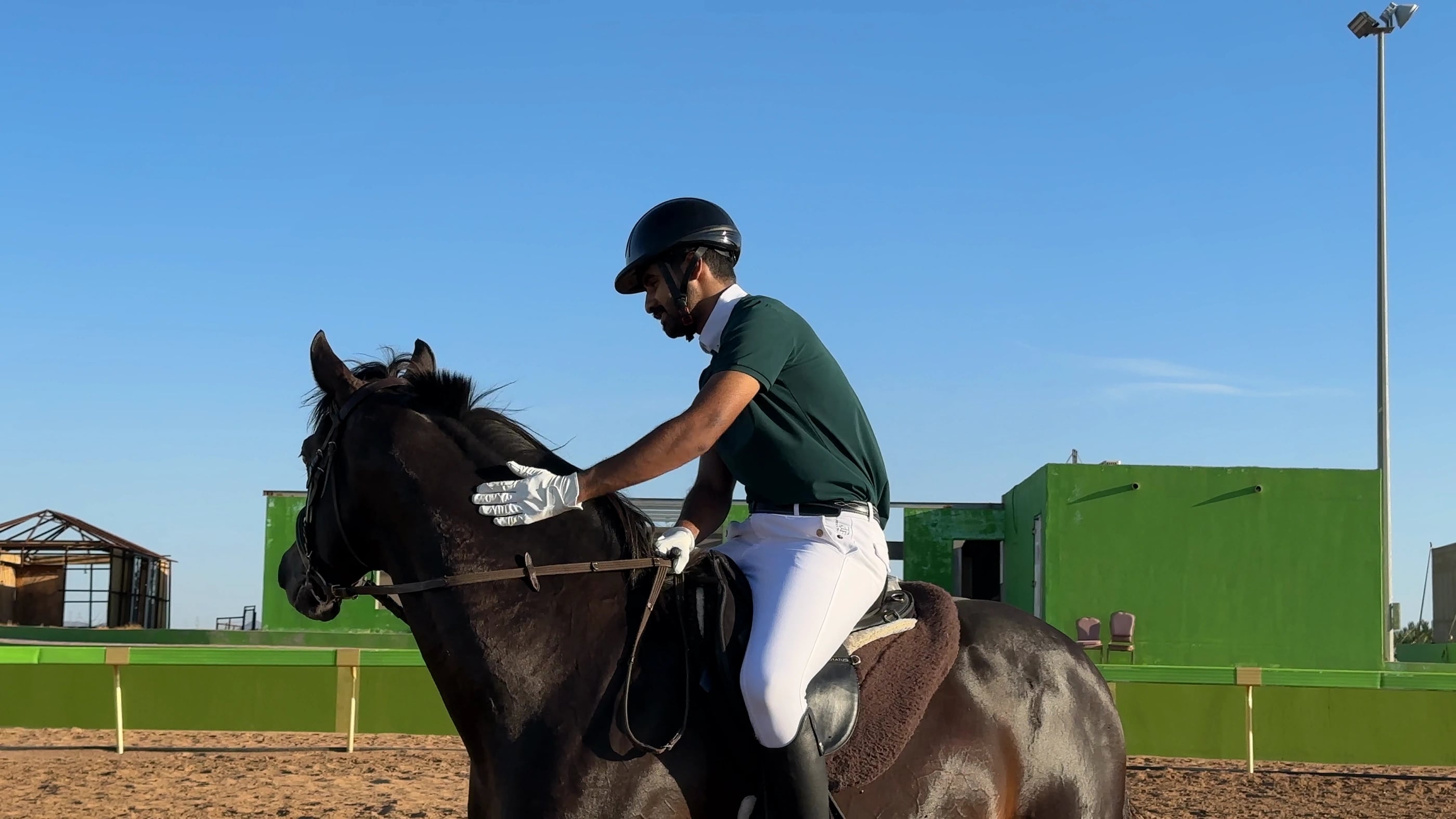 A rider gently patting his horse in the Albarraq arena
